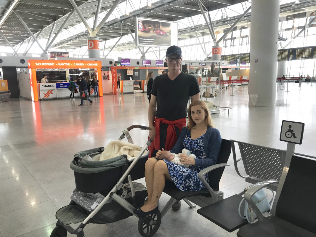 pierwszy lot z niemowlakiem A family waiting at the airport with their baby and stroller before flying