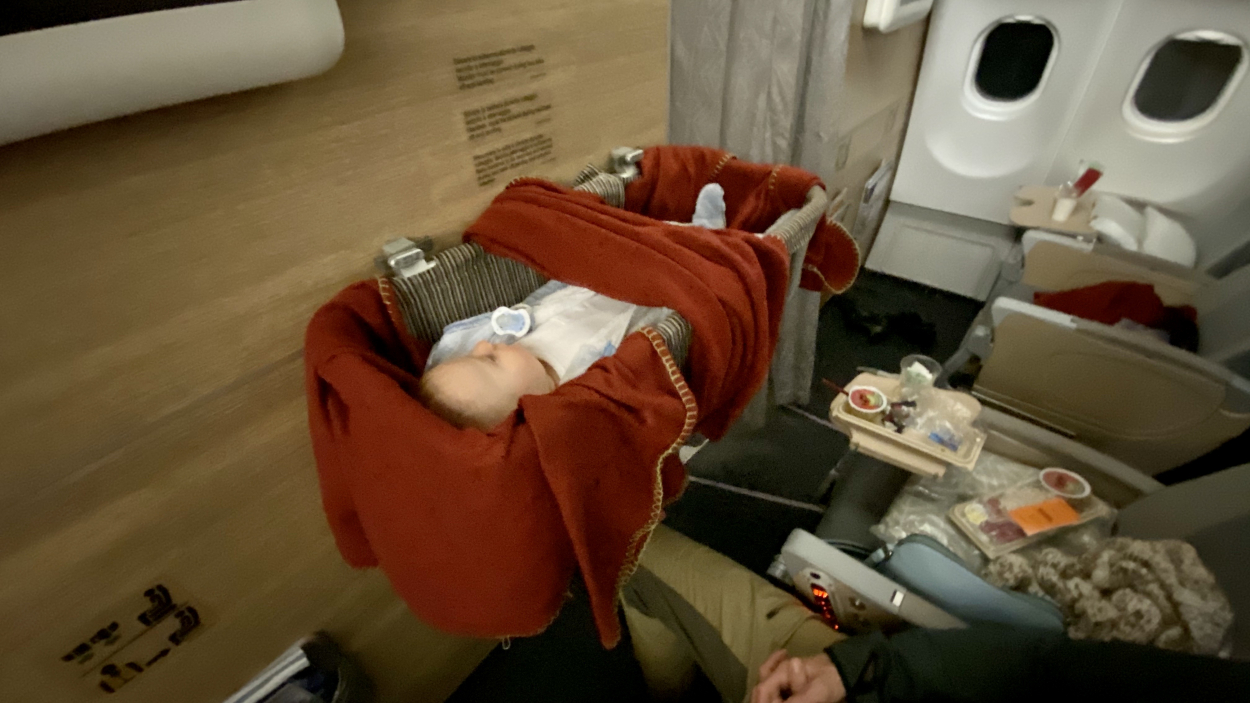 baby bassinet on plane baby asleep in a bassinet on plane, one seating option when flying with a baby